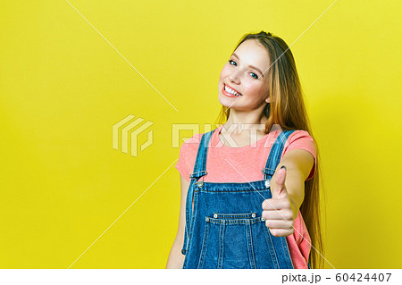 Happy excited woman smile holding thumbs up gesture, beautiful young woman smile looking at camera. isolated ob yellow backgroud. Happy excited woman smile holding thumbs up gesture, beautiful young woman smile looking at camera. isolated ob yellow backgroud. 60424407