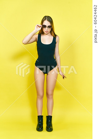Model in body and boots posing on a yellow background 60424462