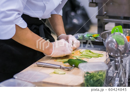 Chef hands peels and slices fresh green cucumber 60424845