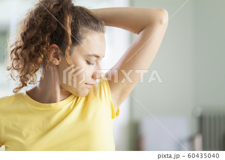 Young woman smelling her armpits Young woman smelling her armpits 60435040