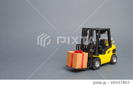 Yellow forklift truck carries a gift with a red bow. Purchase and delivery of a present. retail, discounts and contests. sweepstakes and contest promotions. Increase sales and attract new customers. 60437807