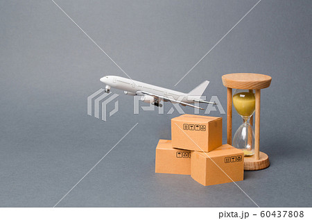 Airplane takes off behind the stack of cardboard boxes and a sand clock. concept of air cargo and parcels, airmail. Fast delivery of goods and products. Cargo aircraft. Logistics, connection 60437808