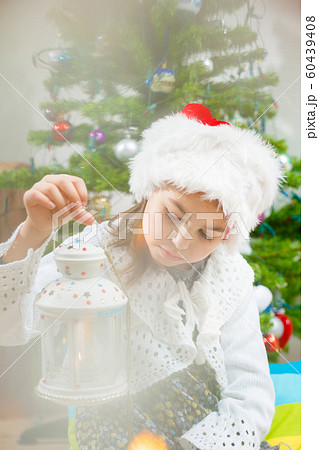 Nice girl in a Christmas hat with a candlestick in her hands, Fur-tree 60439408