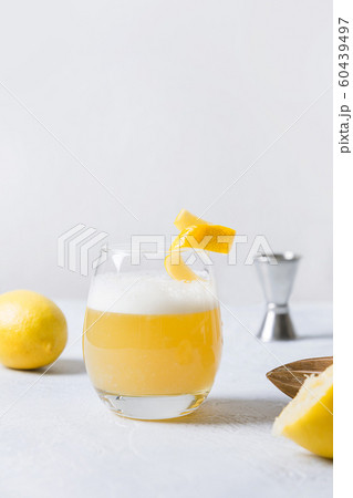 Whiskey sour cocktail - bourbon with lemon juice, sugar syrup and egg white in glass. Vertical orientation. Whiskey sour cocktail - bourbon with lemon juice, sugar syrup and egg white in glass. Vertical orientation. 60439497