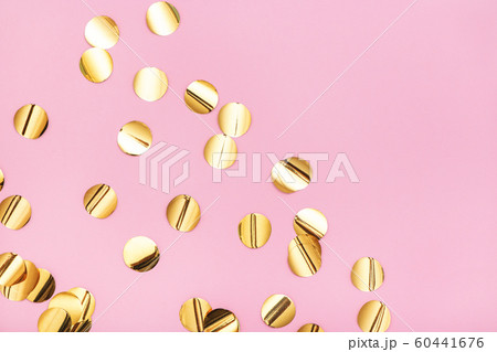 Close up of gold metallic confetti on pastel pink background. 60441676