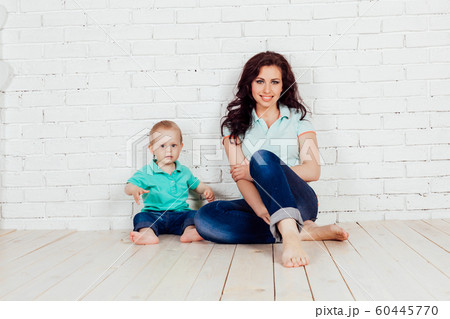 mom and young boy son sit on the floor brick wall mom and young boy son sit on the floor brick wall 60445770