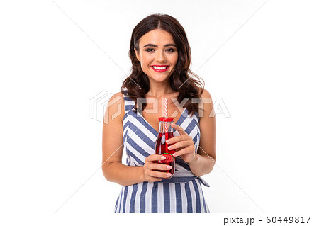 attractive brunette girl in a striped dress with a neckline with a glass of cocktail on a white 60449817