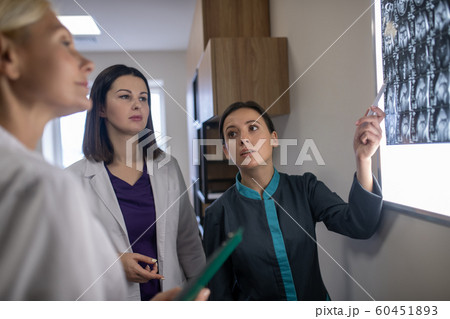 Three female doctors discussing mri brains scan Three female doctors discussing mri brains scan 60451893