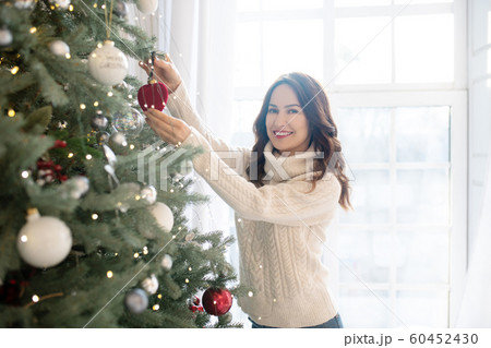 Young pretty smiling woman decorating christmas tree Young pretty smiling woman decorating christmas tree 60452430