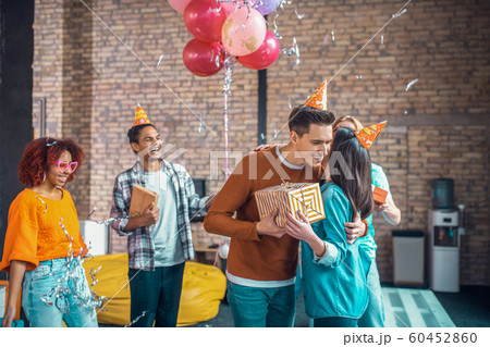 Handsome boyfriend hugging girlfriend while congratulating her on birthday Handsome boyfriend hugging girlfriend while congratulating her on birthday 60452860