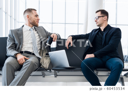 Businessmen working together on laptop in airport lounge Businessmen working together on laptop in airport lounge 60453534