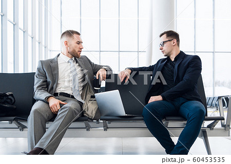 Businessmen working together on laptop in airport lounge 60453535