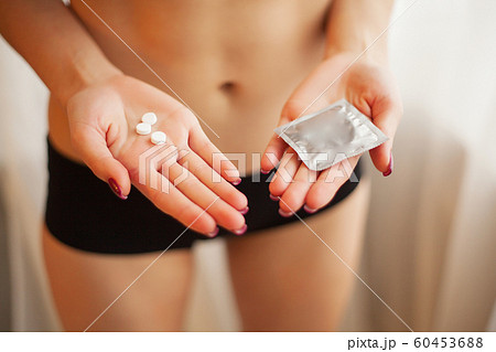 Contraception. Safe sex, choosing a contraceptive. Sexy girl with a condom and pills in her hands 60453688