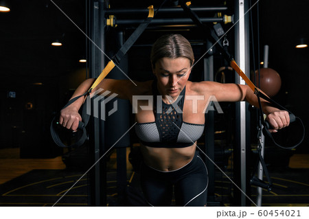Front view of confident young blonde woman doing weight lifting workout Attractive young woman lifting weight looking forward Strong trained body shape arms chest legs. 60454021