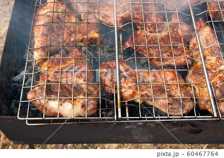 Juicy pork steak cooking on an open flame grill. 60467764