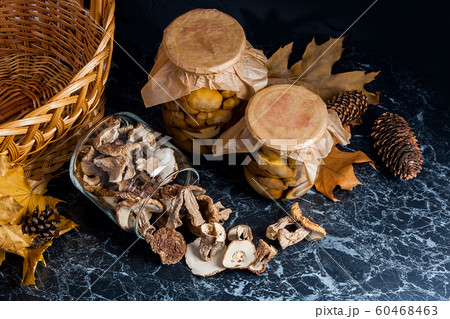 Two glass jars with wild mushrooms on black marble 60468463