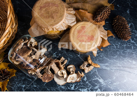 Two glass jars with wild mushrooms on black marble 60468464