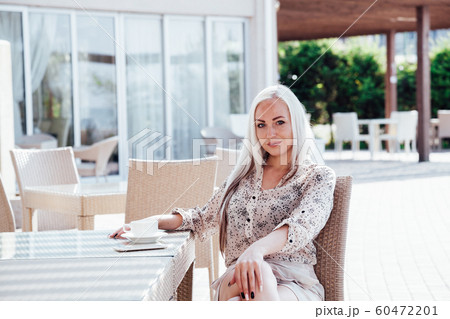 blonde girl sitting at the beach restaurant coffee 60472201