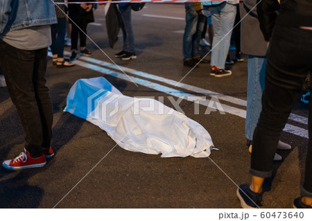 Human body covered by a sheet lying on the street. 60473640