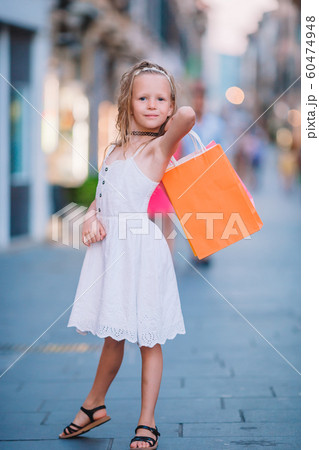 Portrait of adorable little girl walking with shopping bags outdoors in european city. Portrait of adorable little girl walking with shopping bags outdoors in european city. 60474948