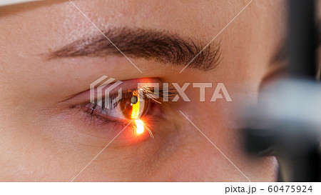 A young woman checking her visual acuity with a light of special big optometry machine - brown eyes color A young woman checking her visual acuity with a light of special big optometry machine - brown eyes color 60475924
