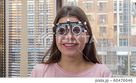 Ophthalmology treatment - a young smiling woman sitting in the optometry device for vision test 60476046