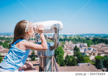 Beautiful girl looking at coin operated binocular on terrace at small town in Tuscany 60476984