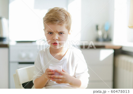 Kid or blonde happy boy eating at table. Childhood and happiness, independence. Breakfast, morning, family. Small boy child eat banana and drink milk. Healthy food and vitamin. dieting, vegetarian 60478013