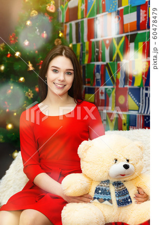 Girl with a teddy bear near the Christmas tree. 60478479