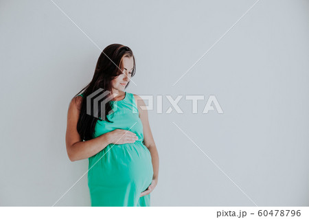 a pregnant woman is standing at the wall next to the window a pregnant woman is standing at the wall next to the window 60478796