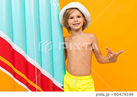 attractive European blond boy in a summer panama with an inflatable swimming board on a yellow 60479396