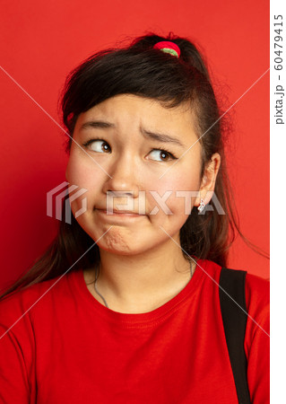 Asian teenager's close up portrait isolated on red studio background 60479415