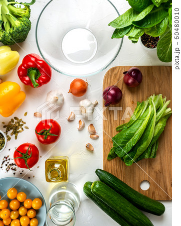 Romaine lettuce on the board and Different vegetables and spices on the table. Ingredients for cook salad. Healthy diet vegan food concept. Top view. Romaine lettuce on the board and Different vegetables and spices on the table. Ingredients for cook salad. Healthy diet vegan food concept. Top view. 60480010