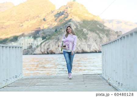 A woman in full figure standing on a wooden pier on the background of mountains A woman in full figure standing on a wooden pier on the background of mountains 60480128