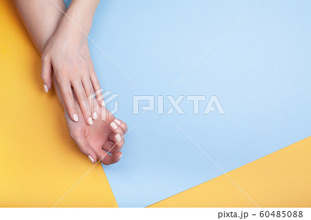Beautiful female hands with a classic matte manicure on a blue-yellow background 60485088