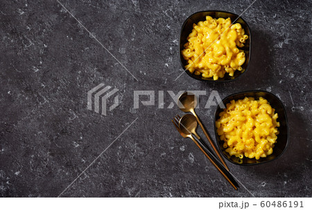 Mac and cheese into two black bowls on dark 60486191