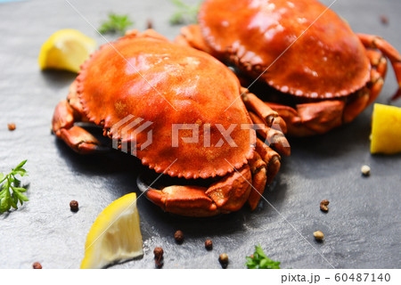 Cooked crab on dark plate with lemon herbs and 60487140