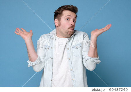 Confused caucasian man is unsure in studio shrugging shoulders up 60487249
