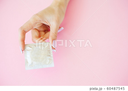 Contraception. Birth Control Pills and an unwrapped Condom. Colored Pills And Capsule On Pink Background. Pharmacy Theme, Capsule Pills With Medicine Antibiotic in Packages 60487545