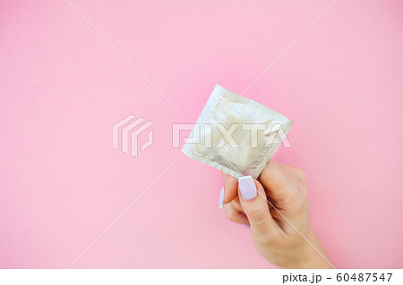 Contraception. Birth Control Pills and an unwrapped Condom. Colored Pills And Capsule On Pink Background. Pharmacy Theme, Capsule Pills With Medicine Antibiotic in Packages 60487547