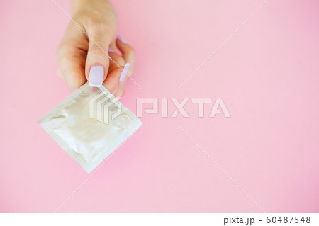 Contraception. Birth Control Pills and an unwrapped Condom. Colored Pills And Capsule On Pink Background. Pharmacy Theme, Capsule Pills With Medicine Antibiotic in Packages 60487548