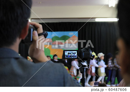 学芸会で劇を発表する我が子を懸命に撮影する保護者 60487606
