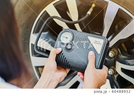 Women inflating tires. with an emergency mini air compressor when car tire leaks while traveling. 60488932