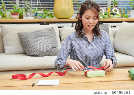 メッセージカードを書いてプレゼントをラッピングする若い女性 メッセージカードを書いてプレゼントをラッピングする若い女性 60496261