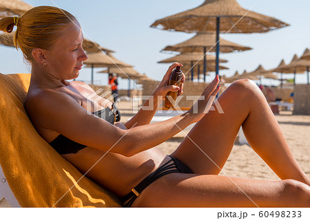 Sensuous slim woman applying suntan oil 60498233