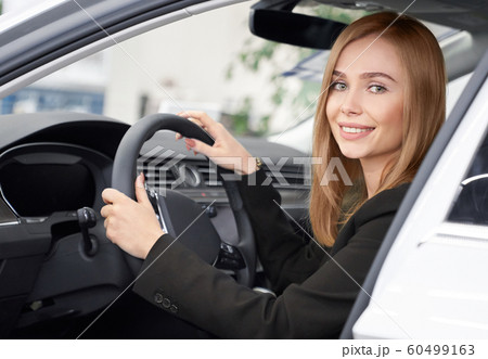 Female customer of auto salon sitting in white car 60499163