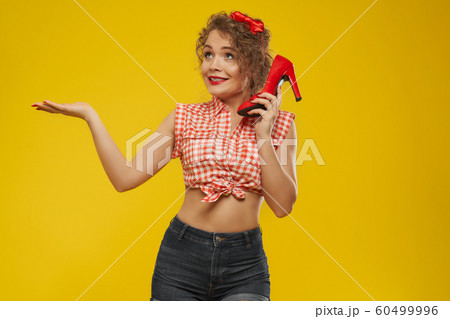 Girl with curly hair, red bow holding one red heel shoe. Girl with curly hair, red bow holding one red heel shoe. 60499996