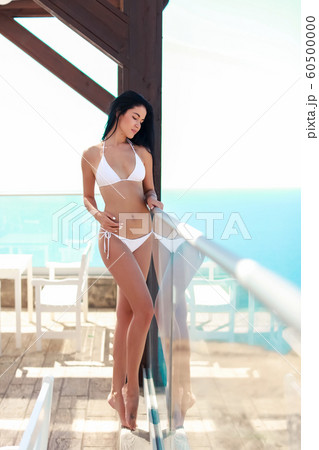 A woman is a young model with long beautiful legs and loose hair in a bikini swimsuit 60500000