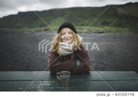 Young woman wearing warm clothing at picnic table on beach 60500746