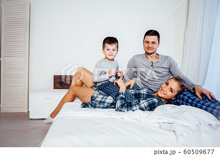 mom dad and son in the morning lying on the bed at home in a good mood mom dad and son in the morning lying on the bed at home in a good mood 60509677